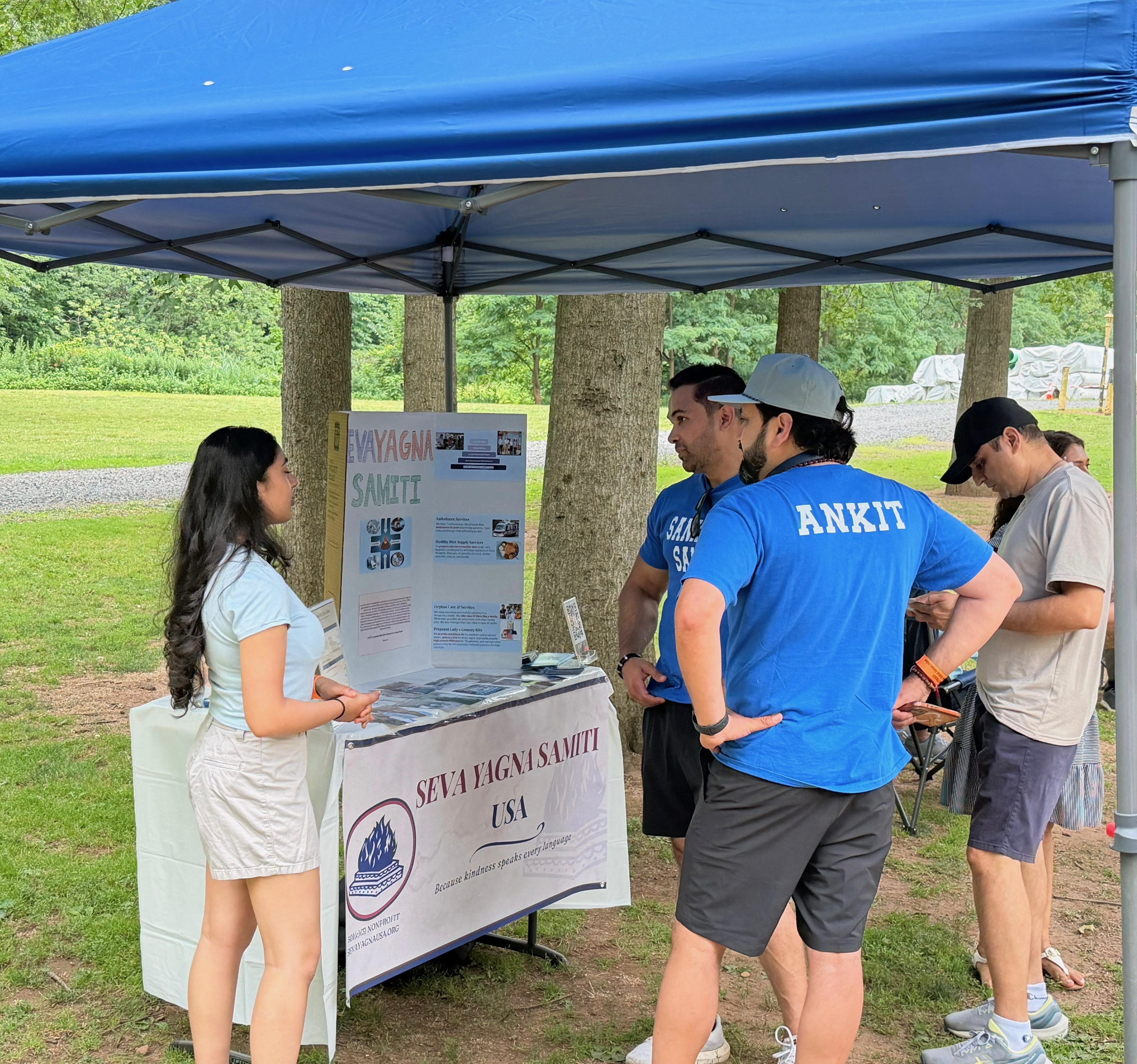 Seva Yagna Samiti volunteers speaking with attendees at a community fundraising booth